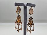 a pair of earrings with gold and black beads on a stand