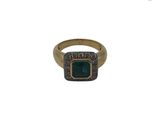 gros plan d'une bague en or avec une pierre verte