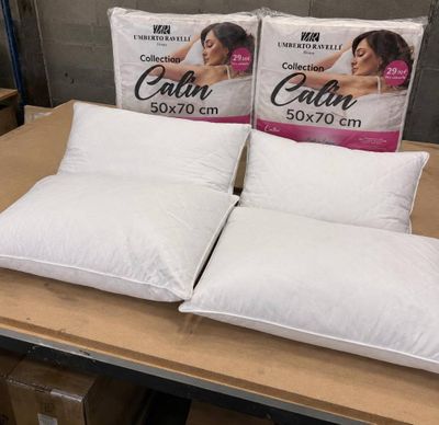 trois oreillers posés sur une table, avec des cartons d'oreillers en arrière-plan