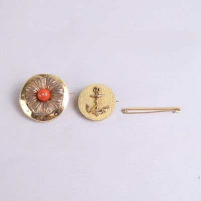 two gold and coral colored buttons and a pin on a white surface
