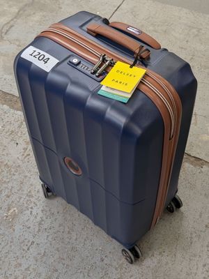 un bagage posé sur le trottoir, auquel est attachée une étiquette