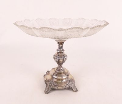 un plat ancien en argent posé sur un socle, sur fond blanc