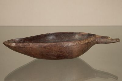 wooden bowl on a glass table with a white wall in the background