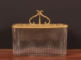 a clear glass box with a gold handle sitting on a wooden table