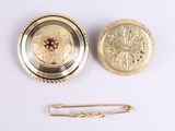 a gold broocht and a pin on a white surface