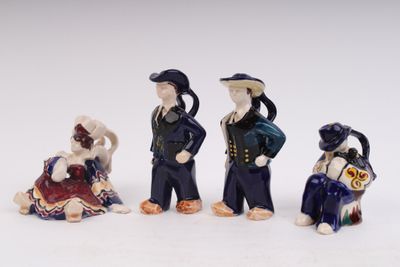 four ceramic figurines of people sitting on a white surface