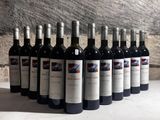 six bottles of red wine lined up in a row on a table
