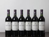 six bottles of wine are lined up on a wooden table