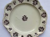 une assiette marron et blanche ornée de fleurs noires, posée sur une table blanche