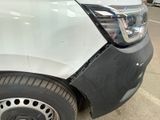the front of a white truck with a dent in it ' s bumper