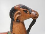 a wooden horse with a black mane on it ' s head