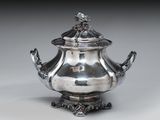 une théière ancienne en argent avec un couvercle, posée sur un socle
