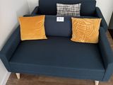 un canapé bleu sur lequel sont posés deux coussins jaunes