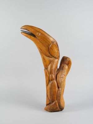 une image représentant une sculpture en bois d'un oiseau, la tête levée vers le ciel