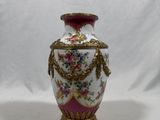 a white vase with a pink and gold decoration on it