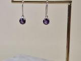 Boucles d'oreilles « Amethorate » sur un présentoir plaqué or, posées sur une table en marbre