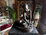 a statue of a woman sitting on a table with a dog