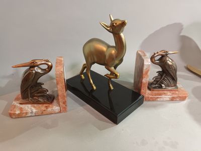 three statues of a deer, a bird, and a bird on a marble base