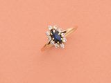 une bague sertie d'un saphir bleu et de diamants sur fond rose