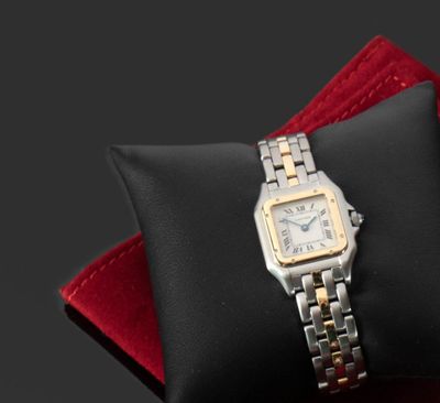 une montre en argent et en or posée sur un coussin noir