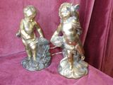 pair of antique bronze figurines of cherensils on a pink background