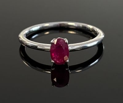 silver ring with a ruby stone on a black surface