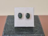 un gros plan sur une paire de boucles d'oreilles en pierre verte posées sur un bloc de marbre