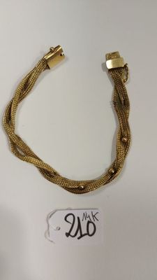 gros plan d'un bracelet en or sur une surface blanche
