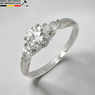 un gros plan d'une bague en diamant à trois pierres sur fond blanc