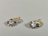 pair of gold and diamond earrings on a white surface