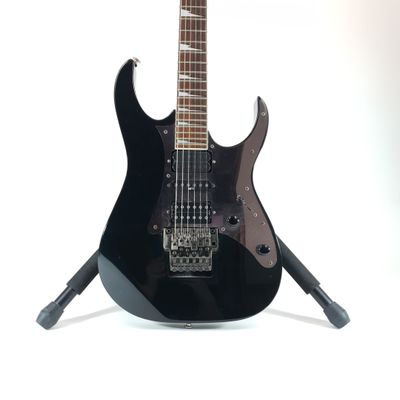 a black electric guitar on a stand on a white background