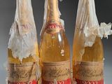 trois bouteilles de vin emballées dans du plastique, posées sur une table