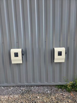 deux prises électriques blanches sur le côté d'un bâtiment métallique