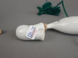 a white vase with a tag on it next to a green string