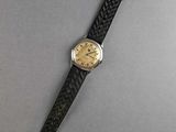 a close up of a watch on a table with a gray background