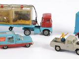 trois petites voitures et un camion posés sur une surface blanche