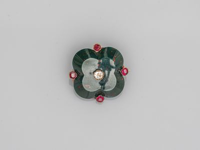 une image montrant un gros plan d'une broche en forme de fleur posée sur une surface blanche