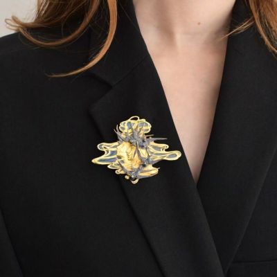 un gros plan sur une femme portant une veste noire et une broche dorée