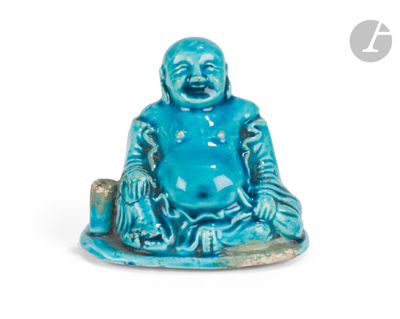 une petite statue bleue représentant un Bouddha souriant, assis sur un rocher