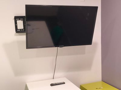 une télévision à écran plat fixée au mur au-dessus d'une petite table