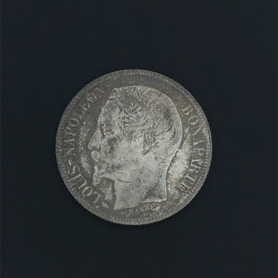 a silver coin on a black surface with a black background