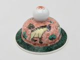 porcelain figurine of a cat on a plate with a ball on top of it