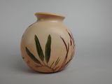 un petit vase avec une plante dessus, posé sur une table