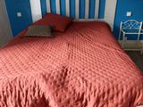 a bed with a red comforter and a white headboard