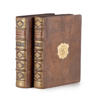 two old books with gold trims on them sitting on a white surface