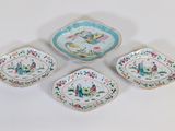 three small dishes with birds and flowers on them on a white surface