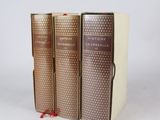 trois livres sont alignés sur une surface blanche
