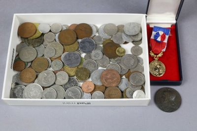 une boîte remplie de pièces et une médaille posées sur une table