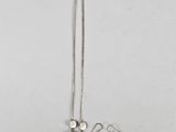 a close up of a necklace and earring on a white surface
