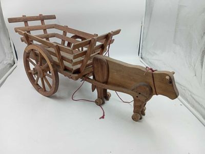 a wooden horse pulling a wooden cart on a white surface